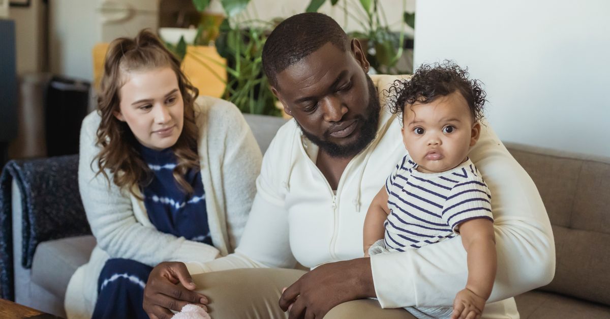 Deux parents réfléchissent ensemble en tenant leur bébé dans les bras dans leur salon