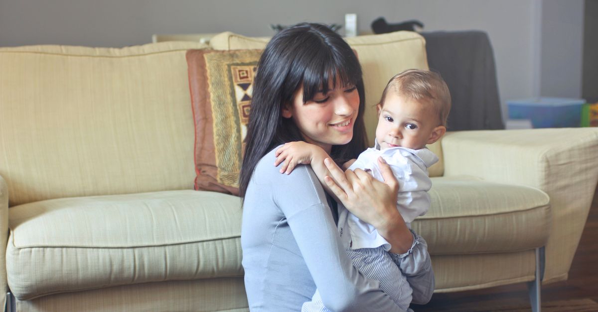 Jeune femme souriante tenant un bébé dans ses bras à la maison, avant la cérémonie en mairie