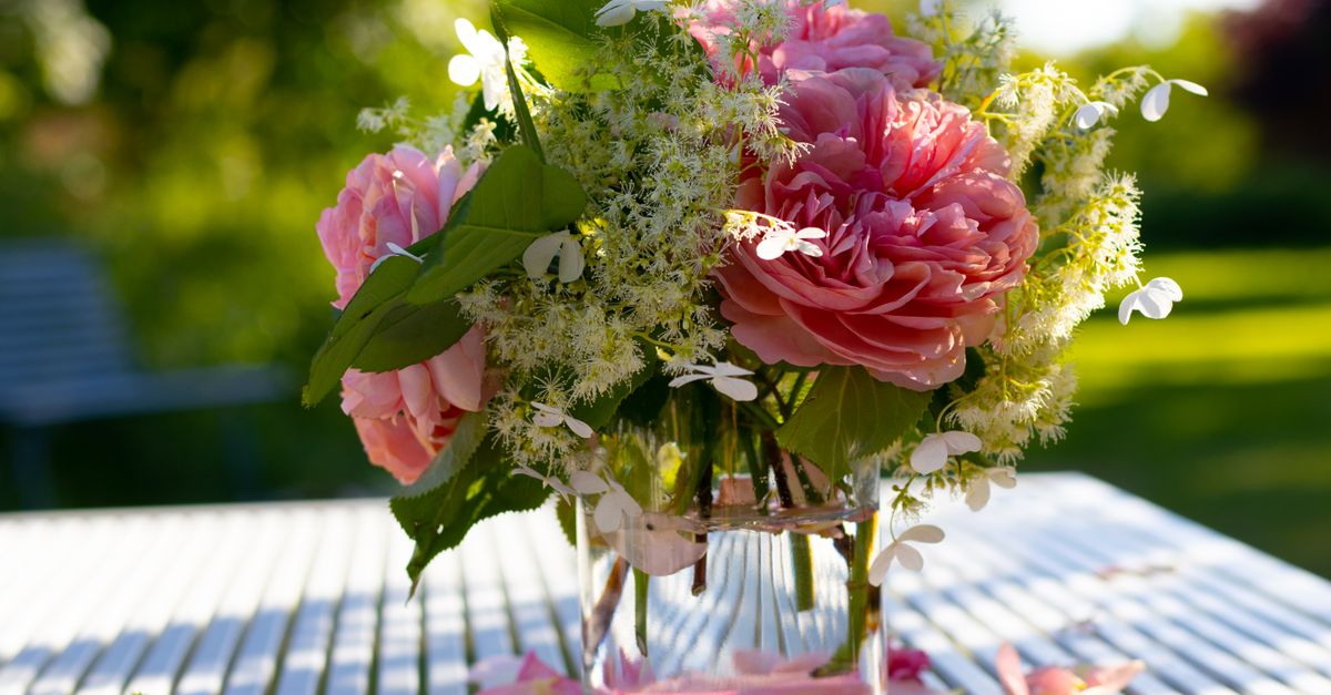 Bouquet champêtre posé sur une table de jardin ensoleillée, décor d'une cérémonie laïque en extérieur