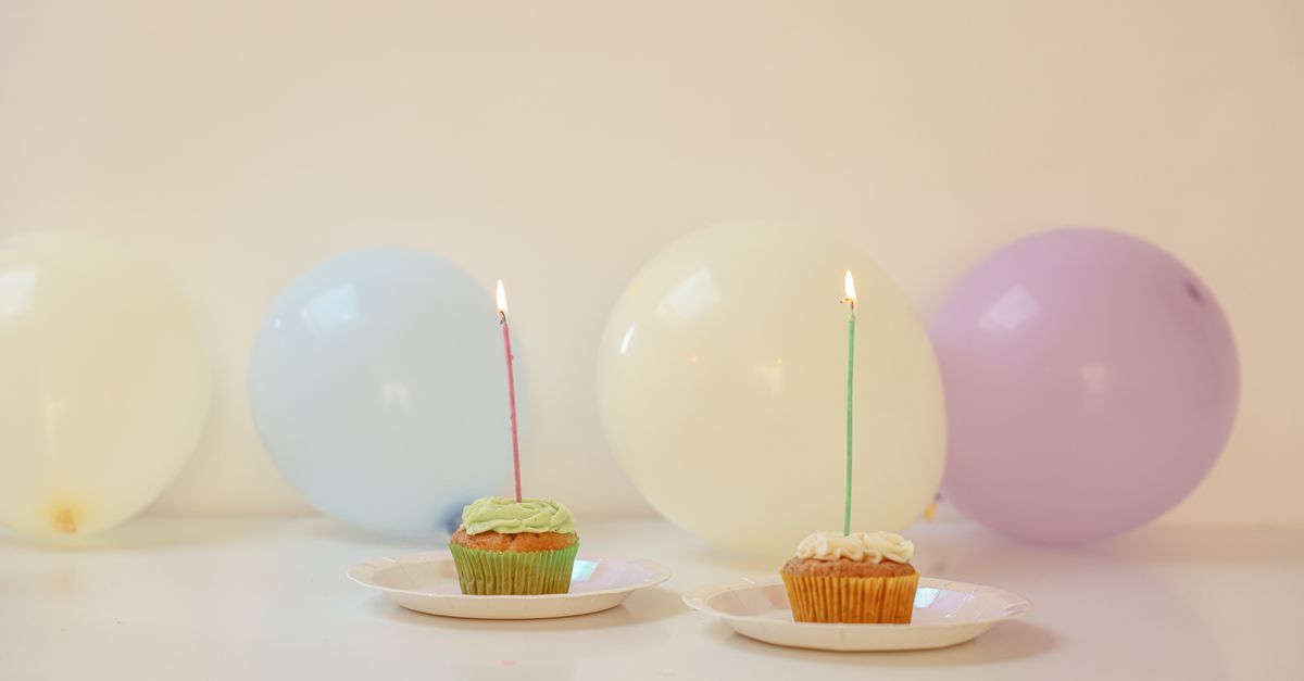 Table de fête pastel avec ballons et petits gâteaux surmontés de bougies, préparatifs de la réception