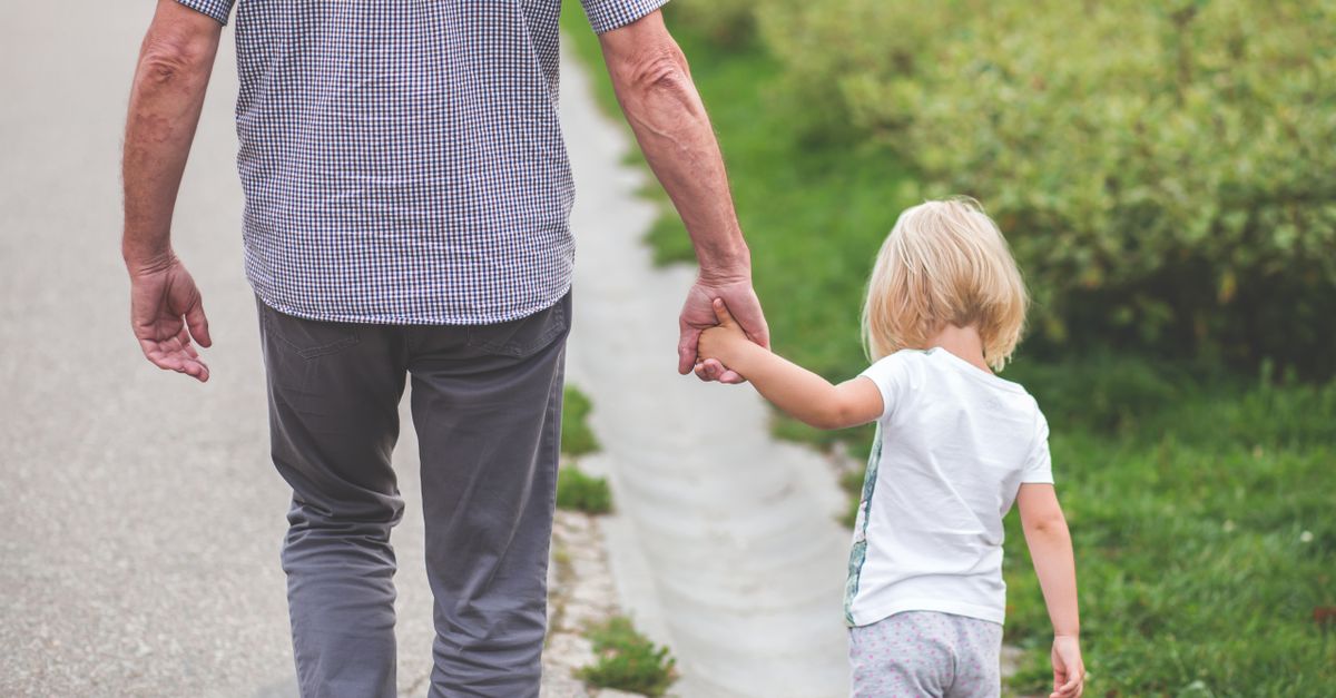 Adulte tenant la main d'un jeune enfant sur un chemin, image de la protection au quotidien