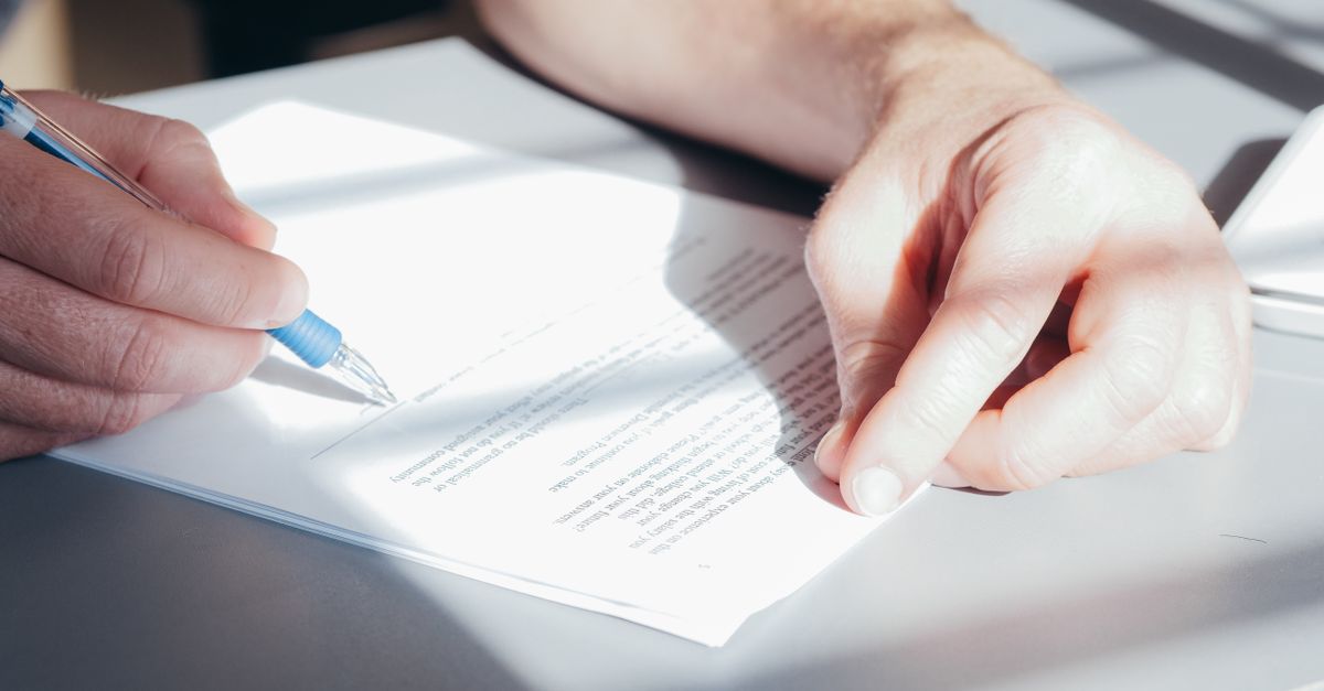 Personne signant un document officiel au stylo, symbole de l'engagement moral du parrainage civil