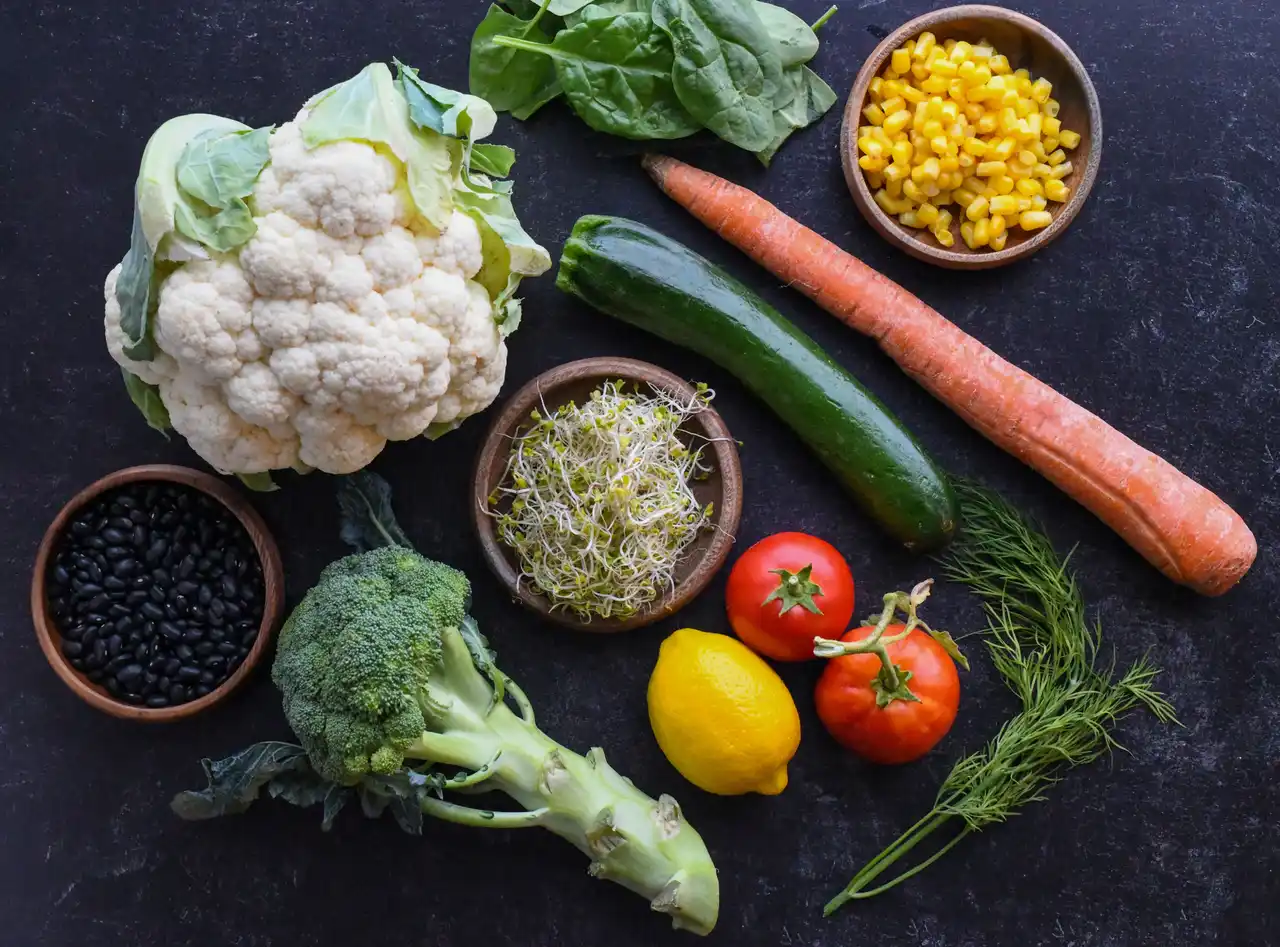 Chou-fleur, épinards, brocoli et haricots noirs disposés sur une table, des aliments riches en folates pendant la grossesse