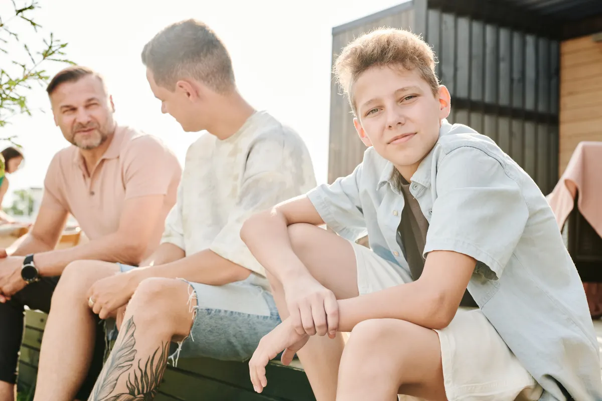 Adolescent assis dehors avec son frère aîné et son père