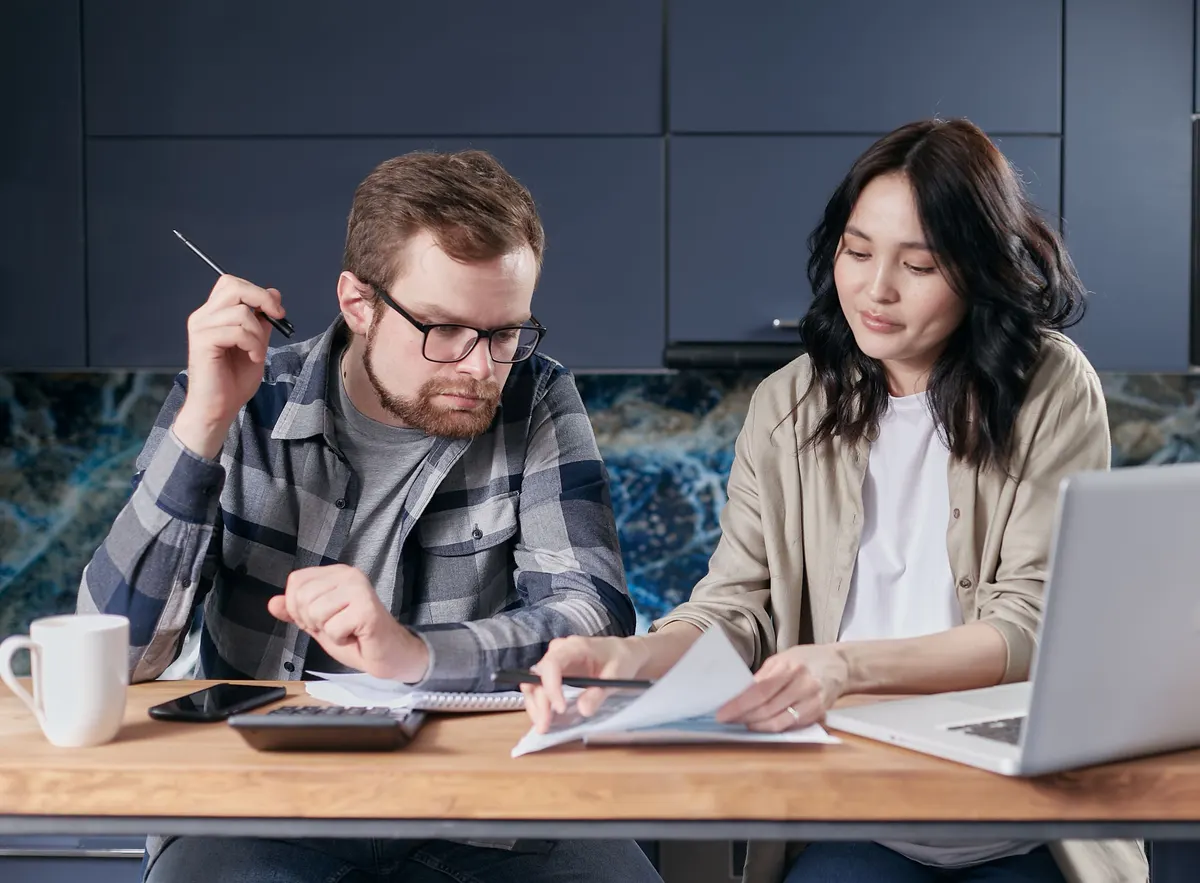 Deux parents examinant leurs factures avec une calculatrice et un ordinateur