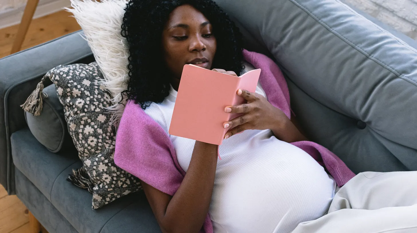 Femme enceinte notant ses démarches dans un carnet sur son canapé