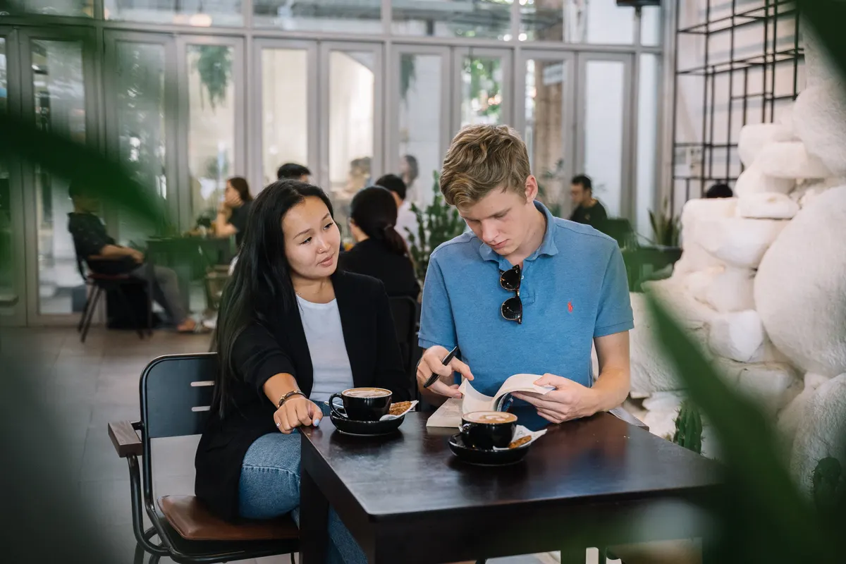 Deux adultes discutant d'un document autour d'un café