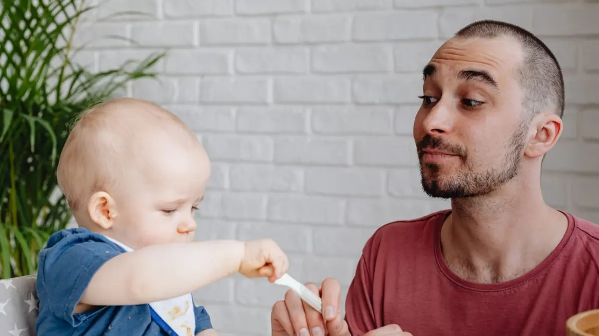Papa donnant la cuillère à son bébé installé dans sa chaise haute
