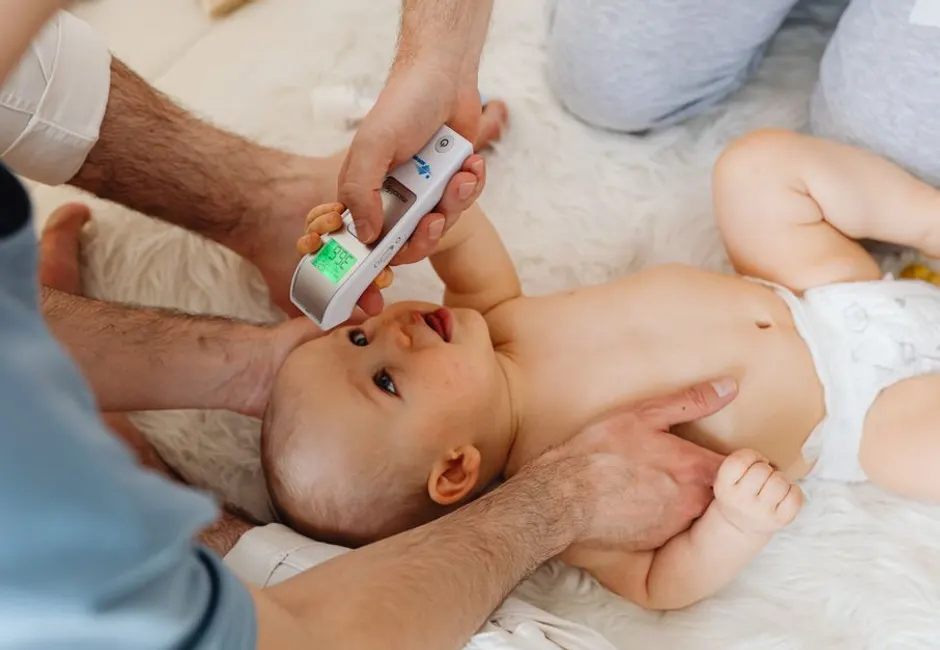 Parent qui prend la température de son bébé pendant une poussée dentaire