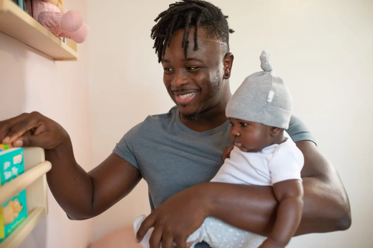 Papa souriant portant son bébé dans la chambre