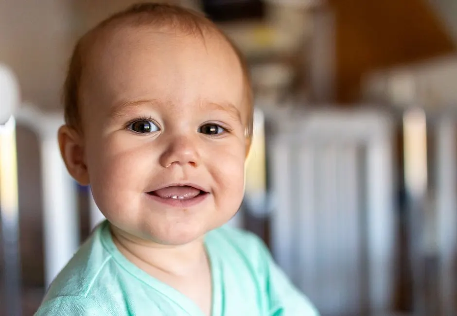 Bébé souriant montrant sa toute première dent sur la gencive du bas