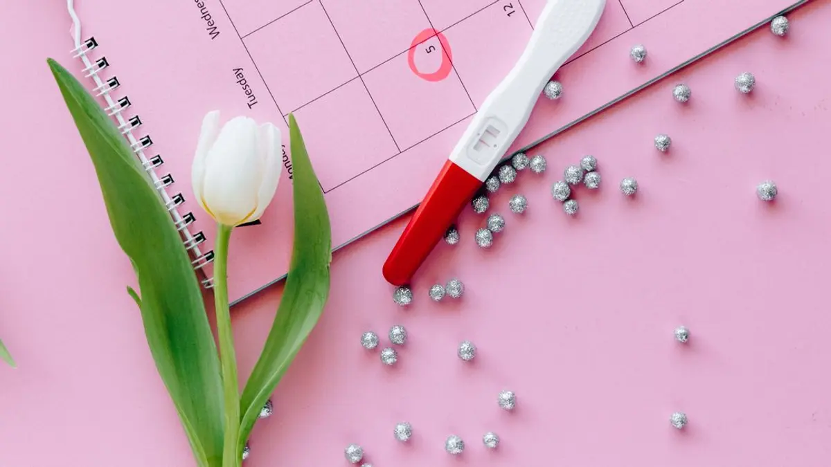 Calendrier avec une date entourée et un test de grossesse posé dessus