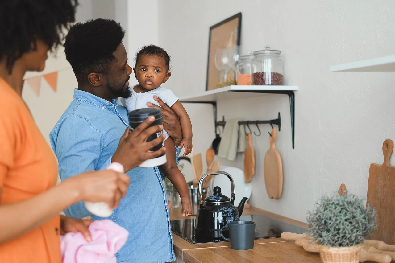 Des parents préparent un biberon dans leur cuisine avec leur bébé