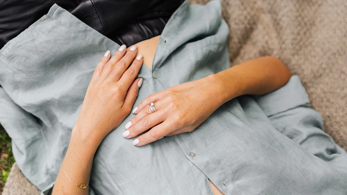 Jeune femme assise sereinement, une main posée sur le bas-ventre, en attente pendant la période de nidation
