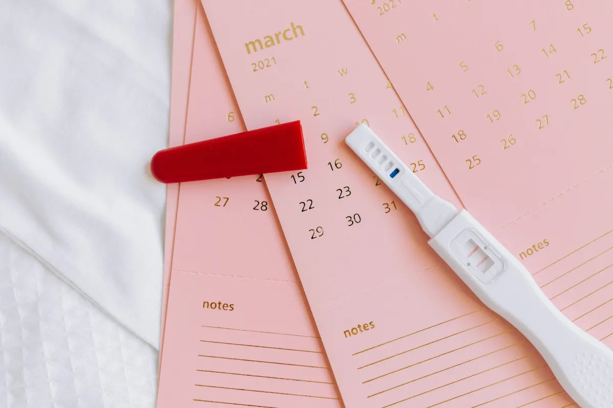Test de grossesse posé sur un calendrier avec une date entourée