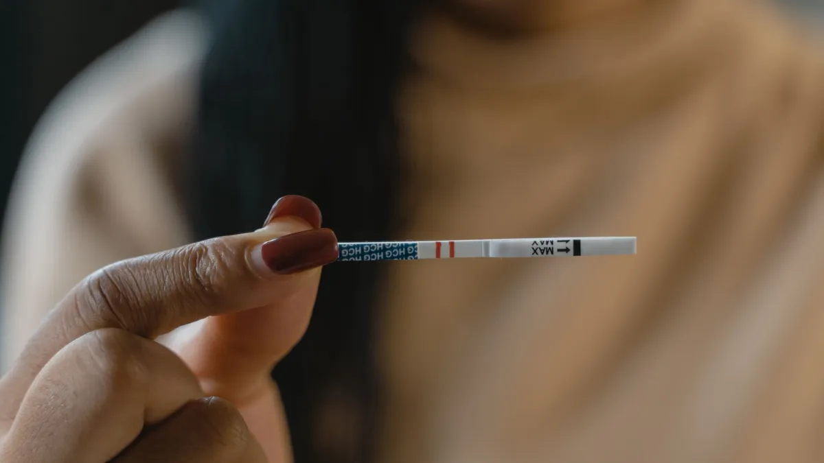 Test de grossesse posé sur une notice ouverte, avec une montre à côté pour respecter le délai de lecture