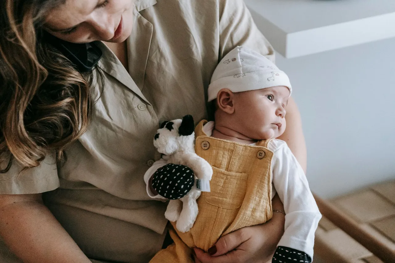 Une mère tient son bébé de quelques mois contre elle, à la maison