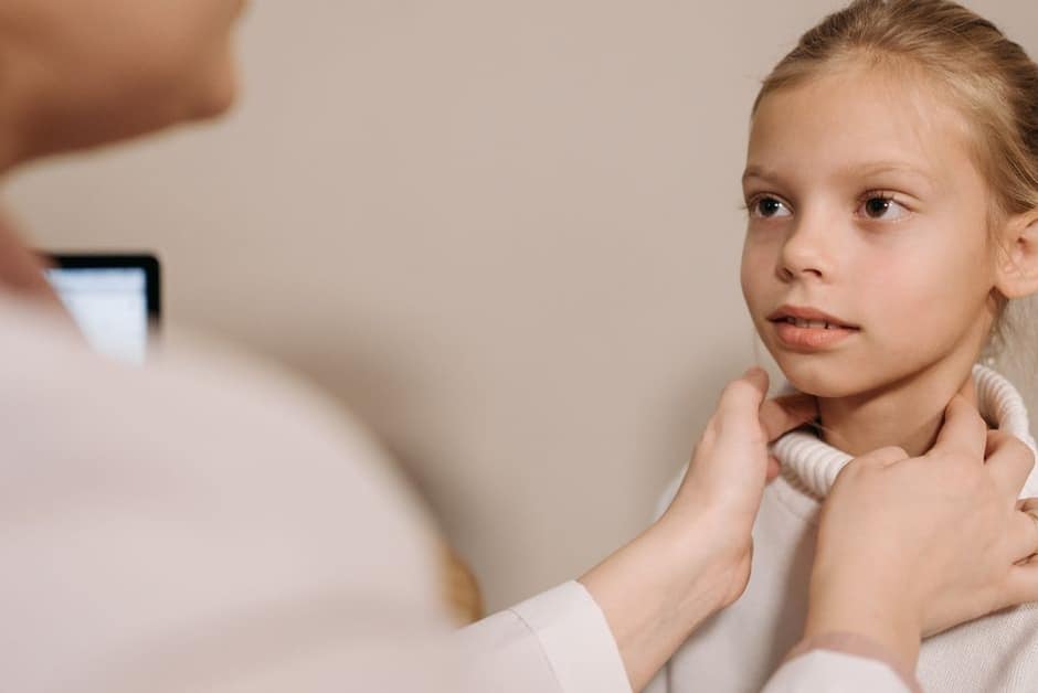 Médecin palpant doucement le cou d'une jeune enfant lors d'un examen de la gorge