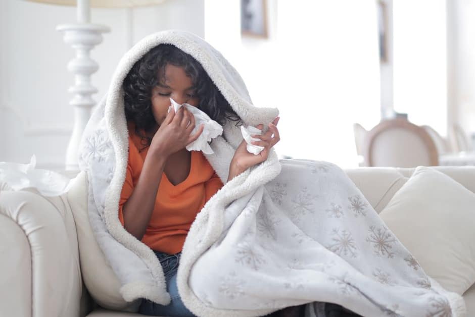 Enfant enrhumée emmitouflée dans un plaid, mouchoirs à portée de main : l'hiver classique en collectivité