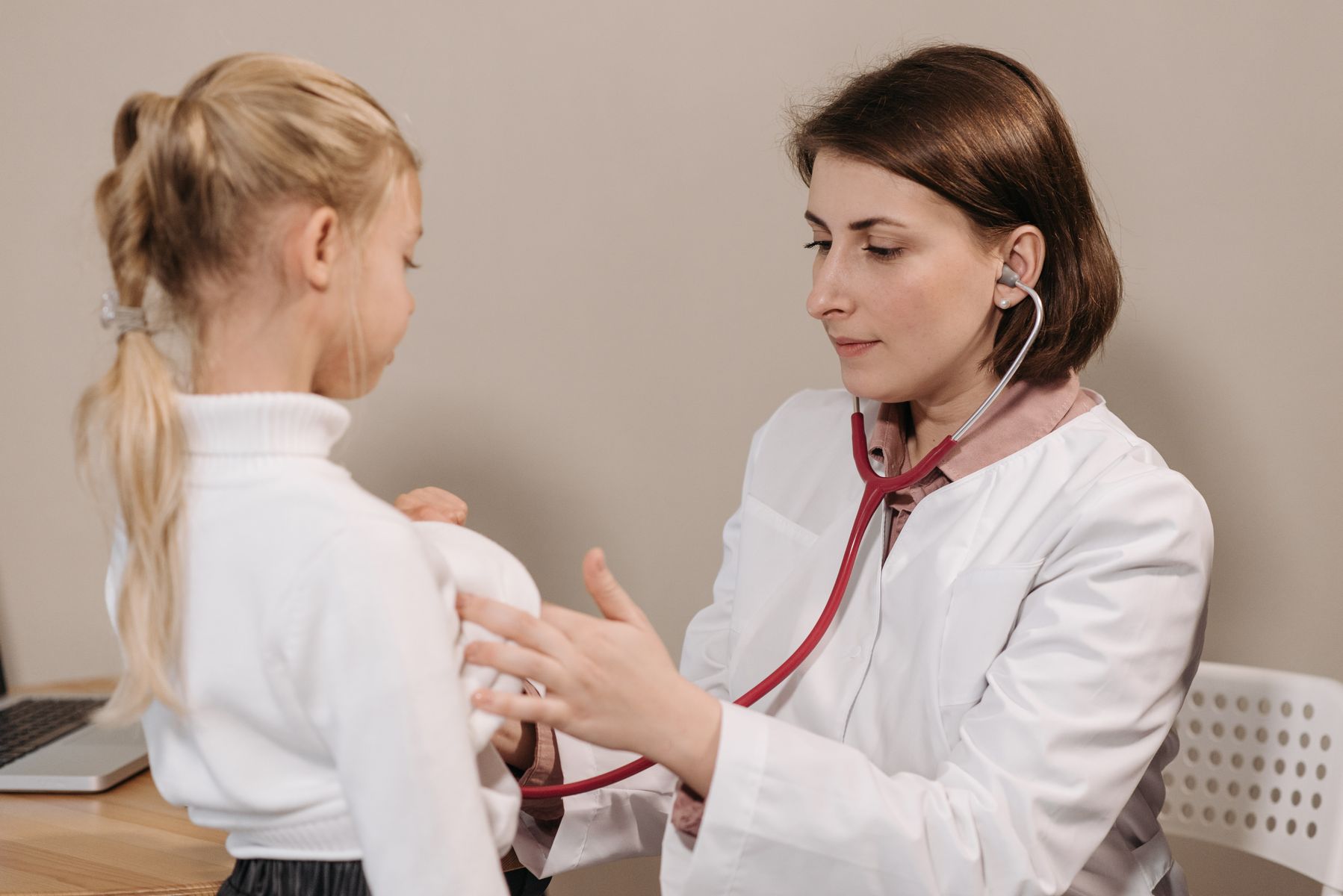 Pédiatre examinant une jeune enfant au stéthoscope lors d'une consultation