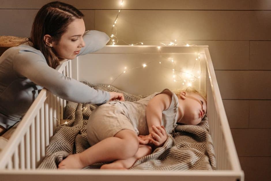 Parent veillant sur son bébé endormi dans son lit à barreaux, le soir