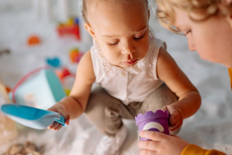 Deux tout-petits jouant côte à côte avec des jouets dans une salle de crèche