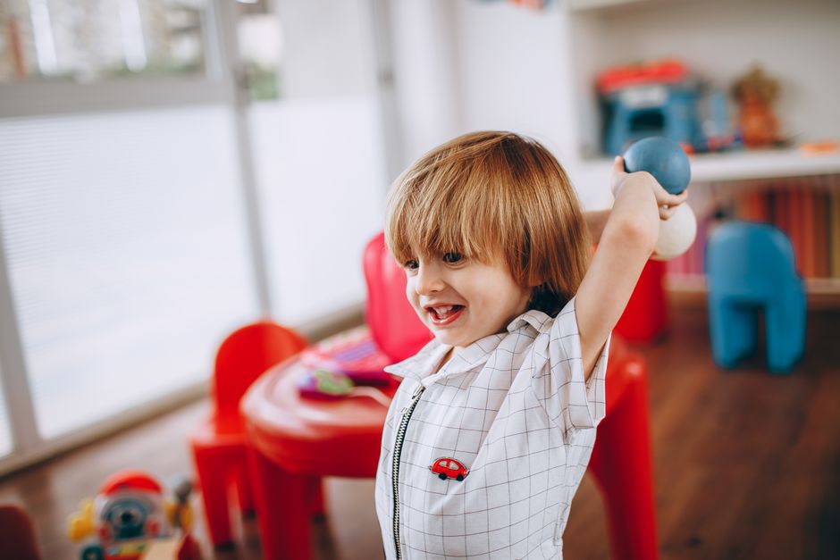 Petite fille jouant seule avec des jouets colorés au sol dans une salle de crèche