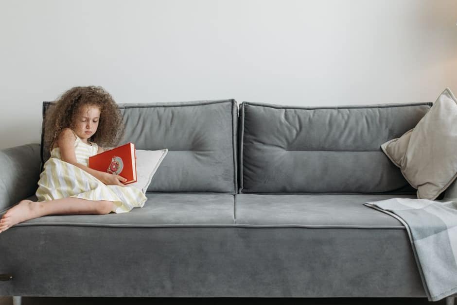 Enfant au repos à la maison sur le canapé, un livre à la main