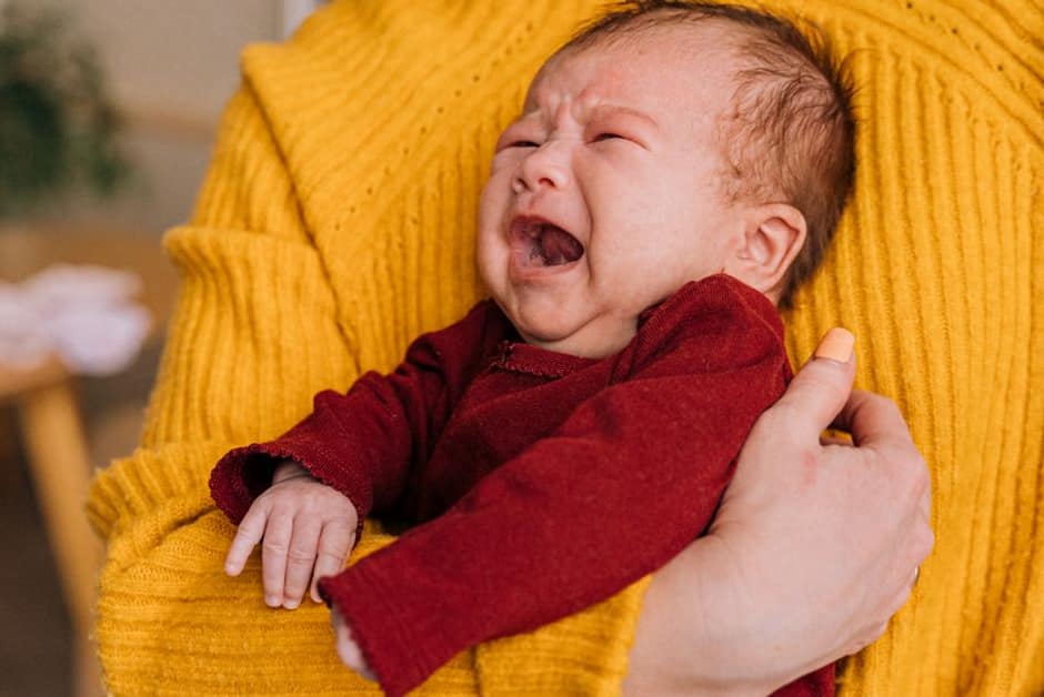 Bébé en pleurs consolé dans les bras de son parent, moment classique d'une otite