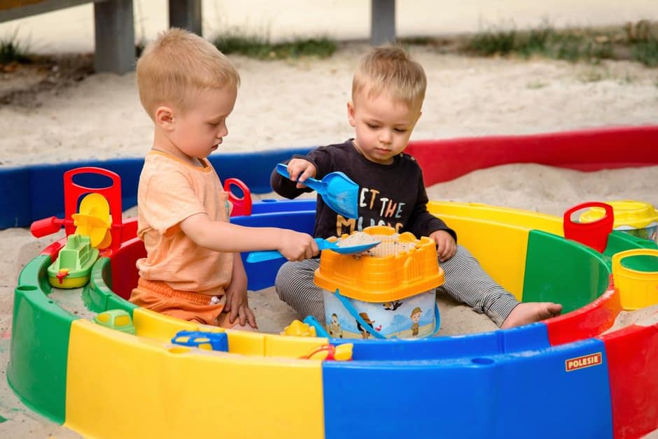 Deux tout-petits jouant ensemble dans un bac à sable, lieu de circulation classique des oxyures