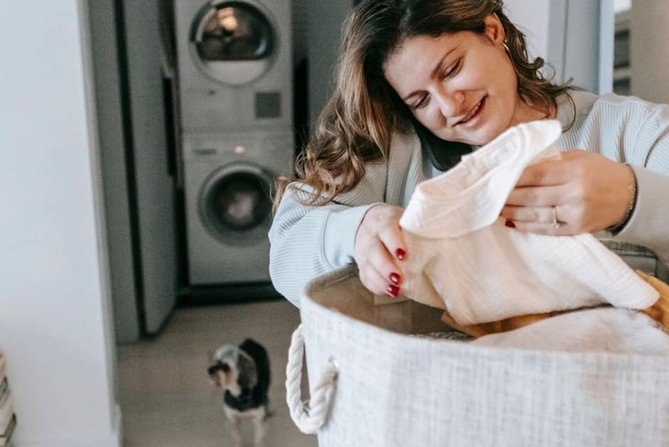 Parent triant un panier de linge devant le lave-linge de la maison