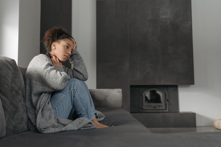 Adulte assis sur un canapé, l'air fatigué, la main sur le visage