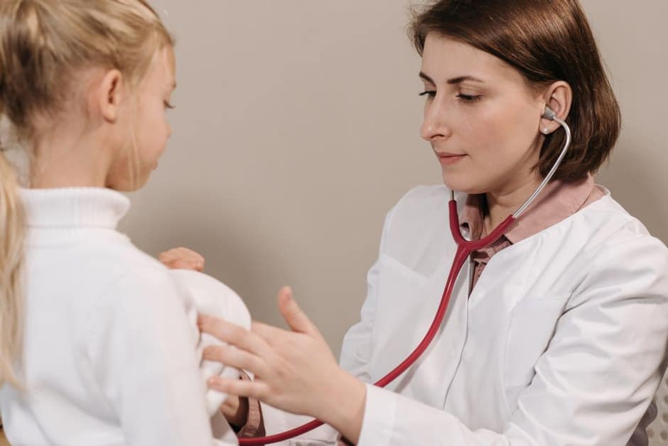 Médecin auscultant une petite fille lors d'une consultation pour une éruption fébrile