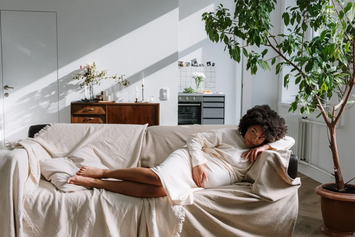 Femme enceinte détendue sur son canapé, une main sur le ventre