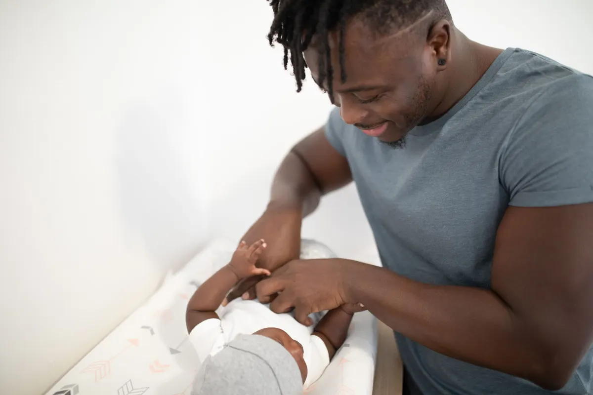 Papa souriant changeant son bébé sur la table à langer