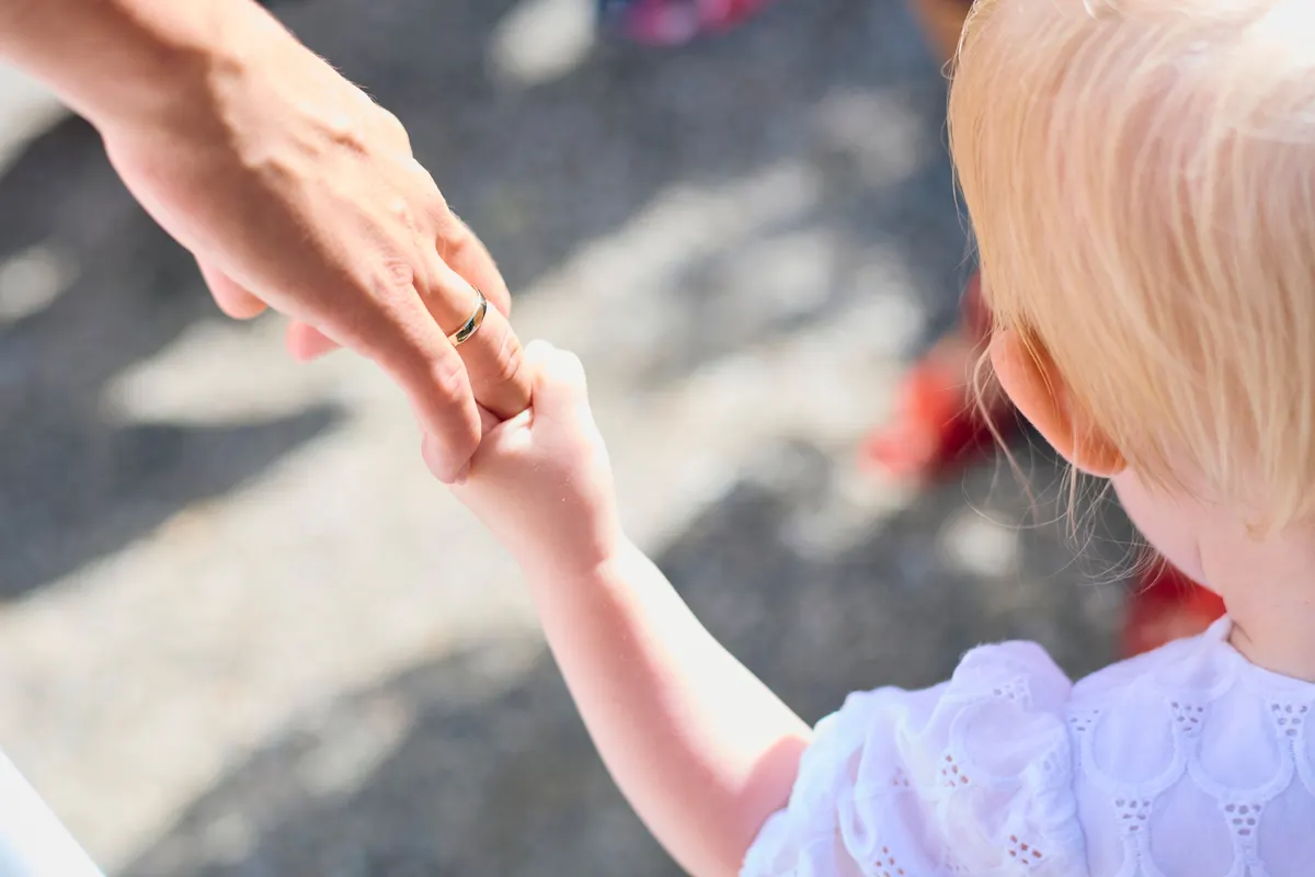 Parent tenant la main de son jeune enfant en promenade