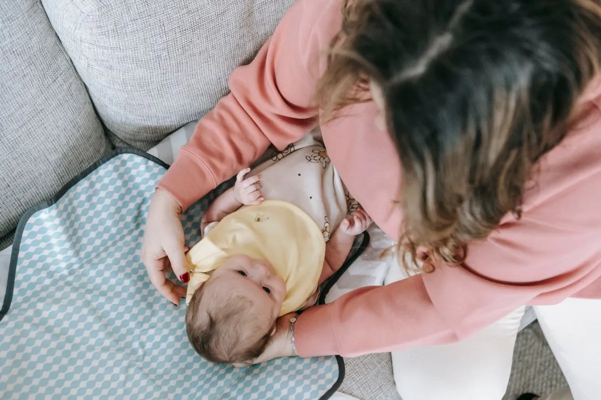 Un nouveau-né d'un mois habillé par sa mère sur un matelas à langer