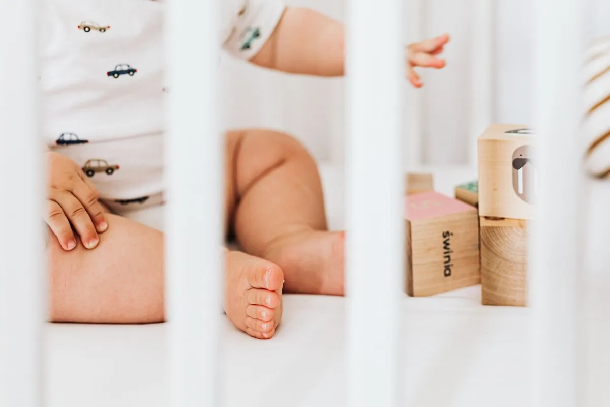 Bébé de 10 mois jouant avec des cubes en bois dans son lit