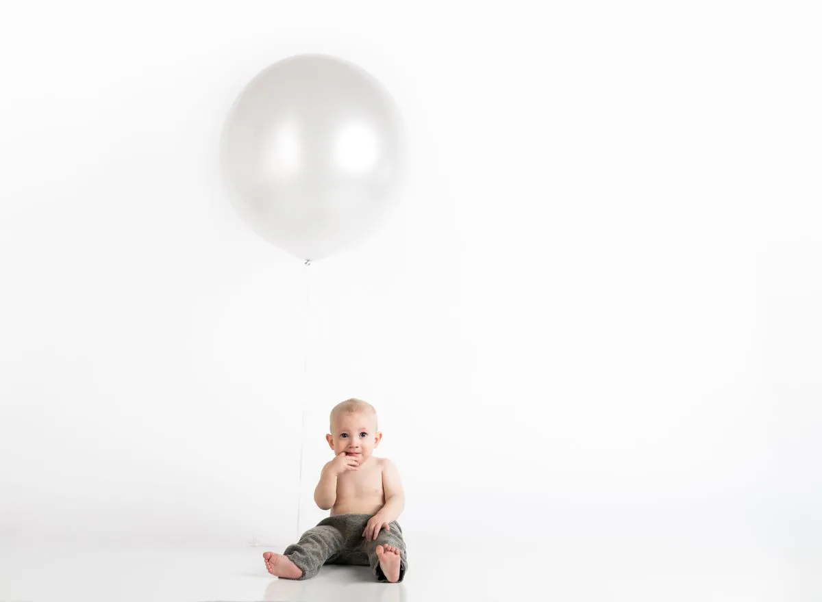 Bébé de 12 mois assis à côté d'un ballon pour son premier anniversaire