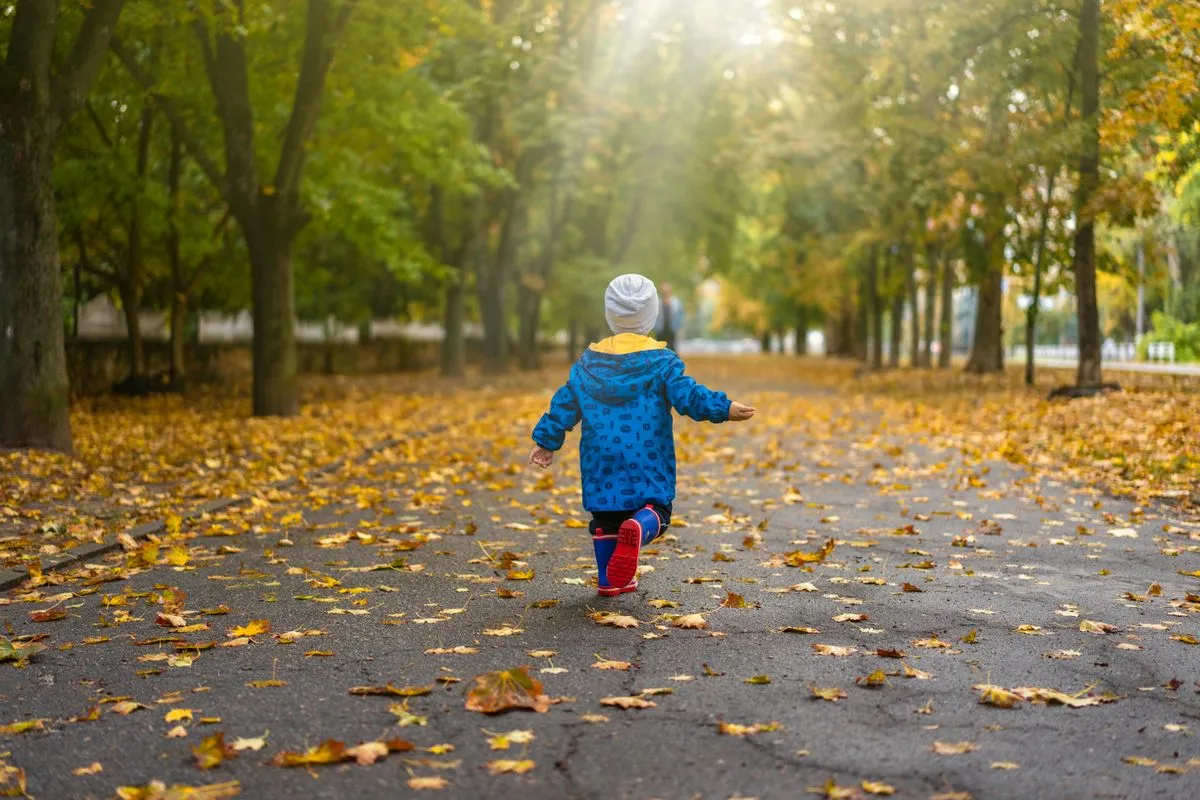 Enfant de 18 mois courant dans les feuilles d'automne