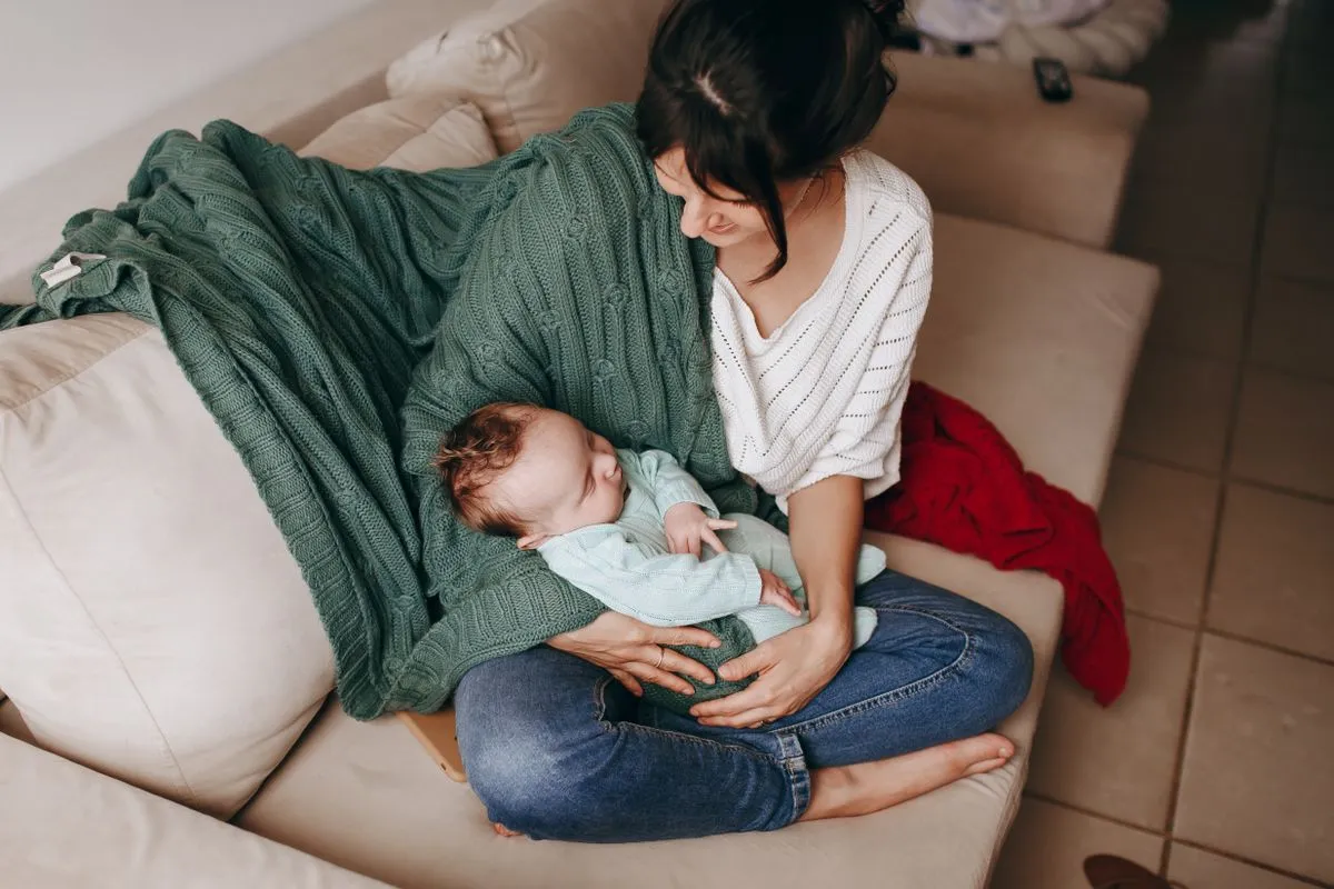 Une mère tient son bébé de 2 mois endormi dans ses bras