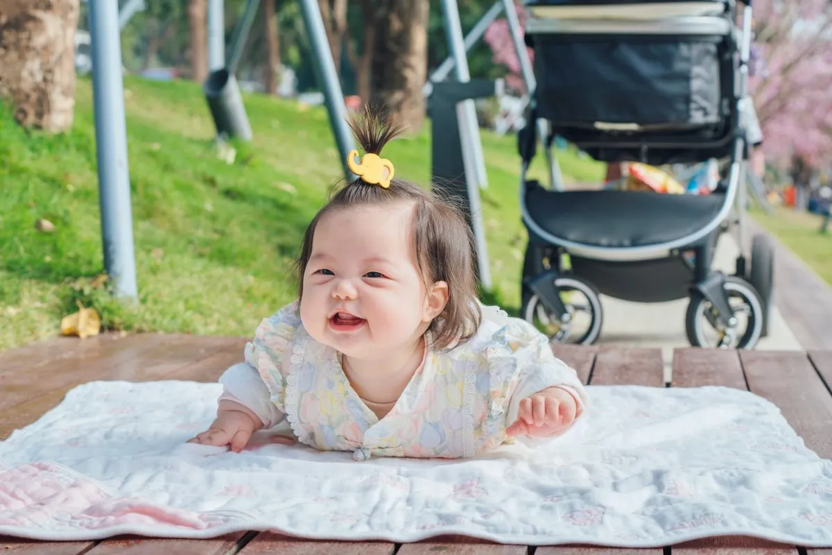 Bébé de 4 mois souriant sur le ventre, la tête bien relevée