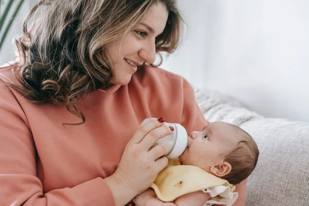 Bébé de 5 mois buvant son biberon dans les bras de sa mère